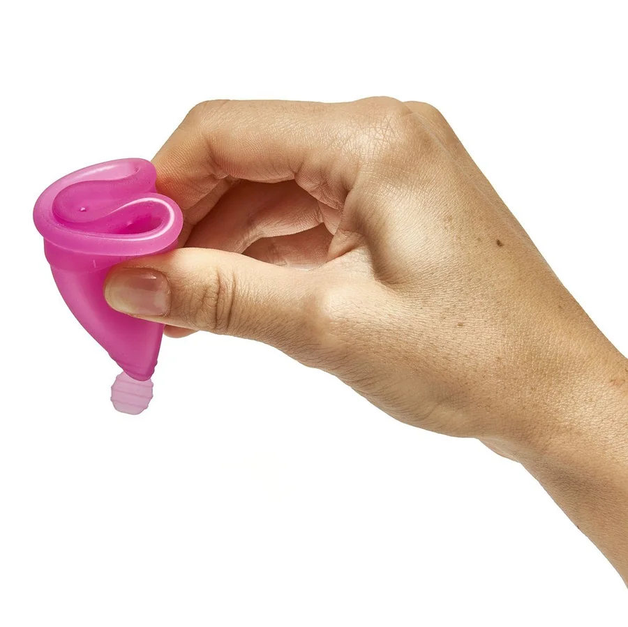 Hand faltet himbeerfarbene Menstruationstasse LUNACUP